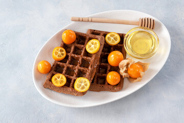 Belgian waffles without flour and sugar with kumquat and physalis for breakfast. The concept of proper nutrition.