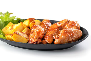 Chicken wings sprinkled with sesame seeds with baked potatoes on a white plate.