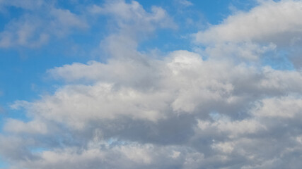 Big white fluffy clouds in the blue sky in sunny weather