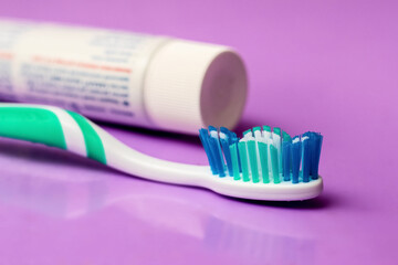 Toothbrush and tube of toothpaste on a purple background. Dental care