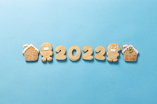 Year 2022, gingerbread man and winter holiday cookies wishing you a happy New Year on a sky blue background