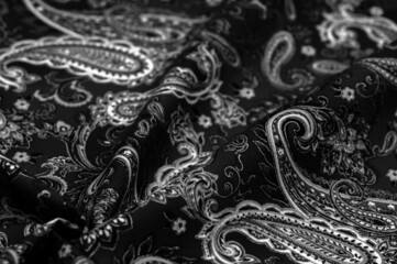 Paisley black-white pattern on a black background. decorated the bandanas of cowboys and bikers popularized by The Beatles, ushered in the era of hippies and became the emblem of rock and roll.