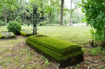 moss-covered old grave with a metal cross