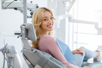 Smiling and relaxed young woman sitting at dental chair - Powered by Adobe