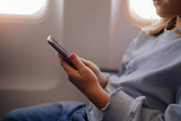 hands of a little girl plays games on smartphone in an airplane seat