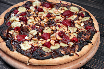 Sweet pizza with chocolate and fruits on black background