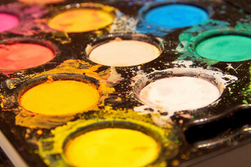 Close-up perspective view of a messy palette with watercolor paints. Hobby and leisure activity backgrounds