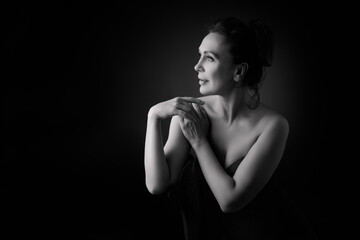 Naklejka premium Portrait of a sensual fifty year old woman on grey studio background. Monochrome shot.