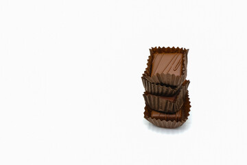 Stack of chocolate candies in paper cups on a white background. Copy space.