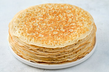 Crepes, thin pancakes with honey and butter on a white plate. Close up.