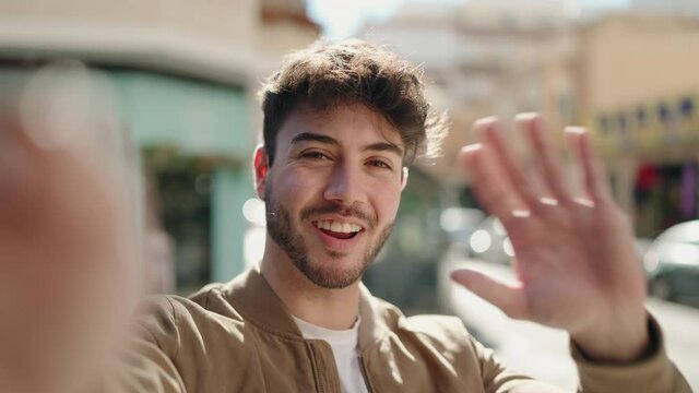 Young hispanic man smiling confident having video call at street