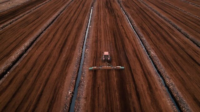 Peat Harvester Tractor on Collecting Extracting Peat. Mining and harvesting peatland. Area drained of the mire are used for peat extraction. Drainage and destruction of peat bogs.