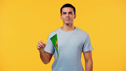 young man in t-shirt holding small flag of brazil isolated on yellow.