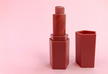 matte lipstick on a pink bright matte background. beige lipstick in the shape of a heart, soft brown shade. nude lip makeup, fashion makeup, lip augmentation with lipstick