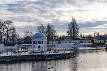 Fototapeta na wymiar City snow-covered park with an artificial pond where wild birds live