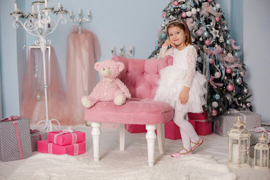 Smiling child girl under Christmas tree with decorations in room.