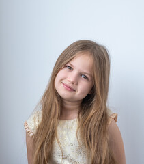 Portrait of cute little caucasian girl smiling on gray background. Adorable kid in in festive gold dress looking at camera.