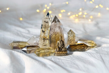 quartz minerals and little Buddha statue on textile abstract background. gemstones crystals for...