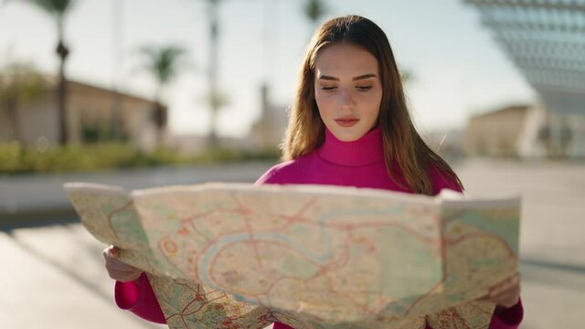 Young blonde woman lost looking city map at street