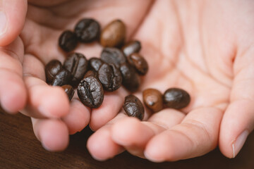 Close up roasted coffee beans are placed in hand.