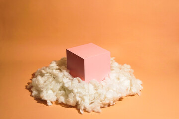 product platform arrangement in pink pastel color decorated with cotton as clouds. trendy display layout with an empty podium for showcasing cosmetics, skincare, or other products.
