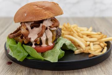 Toasted bun balanced on top of this tall bacon, jalapeno, and gouda hamburger with a generous serving of french fries