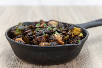 Crispy baked brussel sprouts served as finger food to be eaten out of cast iron pan