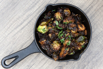 Overhead view of crispy baked brussel sprouts served as finger food to be eaten out of cast iron pan