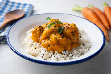 Chicken with carrot sauce on white rice.