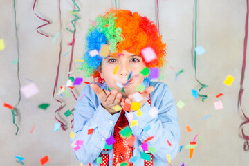 Obraz na płótnie Canvas Funny boy blowing confetti at carnival