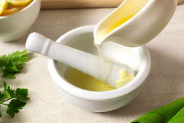 Garlic with lemon juice is mixed with a pestle in a ceramic mortar. Ingredients for making hummus. Boiled chickpeas, tahini, garlic, lemon and butter. A traditional Middle Eastern dish. Step by step.