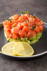 Tartar with salmon, microgreen and avocado served on a plate with lemon