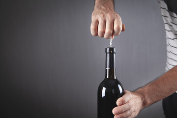 Man opening bottle of wine with corkscrew.