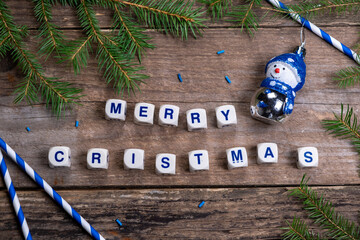 Christmas composition with pine needles and lettering cubes with congratulation - Merry Christmas on wooden boards