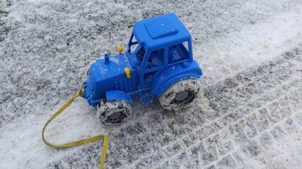 blue tractor on the winter snow road. blue baby toy tractor. children's car toys. 
