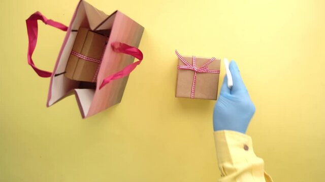 hand in latex gloves wapping a gift box with tissue 