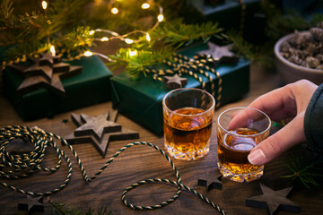 Female hand holding a Glass of whiskey or bourbon with Christmas decor