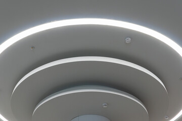 Beautiful designer round-shaped white ceiling with unusual custom-made lamps. The ceiling in the mall. Interior design.
