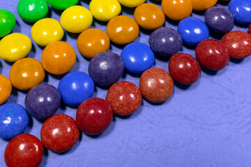 Straight rows of colored candies. Lots of colored sweets on a blue surface