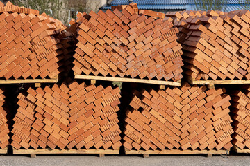 Yellow wooden Pallets with orange bricks outside for building