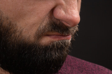 wrinkled grimace of danger, closeup on face and lips of young unrecognizable man with black beard and mustache, concept of rage and anger.