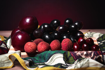frutas de natal e ano novo em taboa de madeira sobre lenço colorido e fundo escuro.