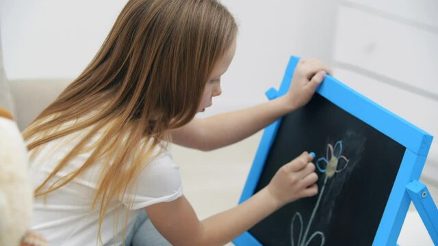 4k video of blonde girl drawing a flower on the white board.