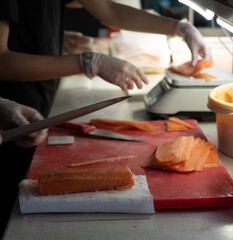 Сhef cuts a red fish with a sharp knife in a restaurant kitchen.