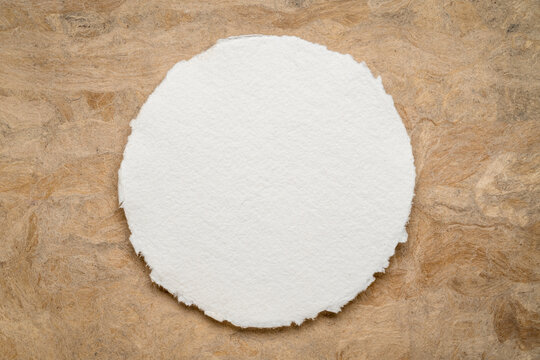 round sheet of blank white watercolor paper against amate bark paper
