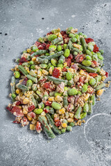 Assortment of frozen vegetables and quinoa with ice. Gray background. Top view