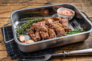 Goulash from lamb and beef meat in a tray with herbs. Wooden background. Top view
