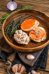 Bruschetta with Hot Smoked salmon, red caviar and herbs. Wooden background. Top view