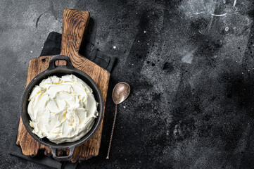 Mascarpone cream cheese in a pan for tiramisu. Black background. Top view. Copy space