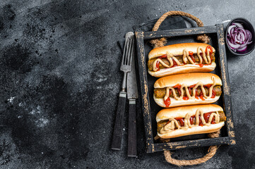 Vegan hot-dog with with assorted toppings and meatless Vegetarian sausage. Black background. Top view. Copy space - obrazy, fototapety, plakaty